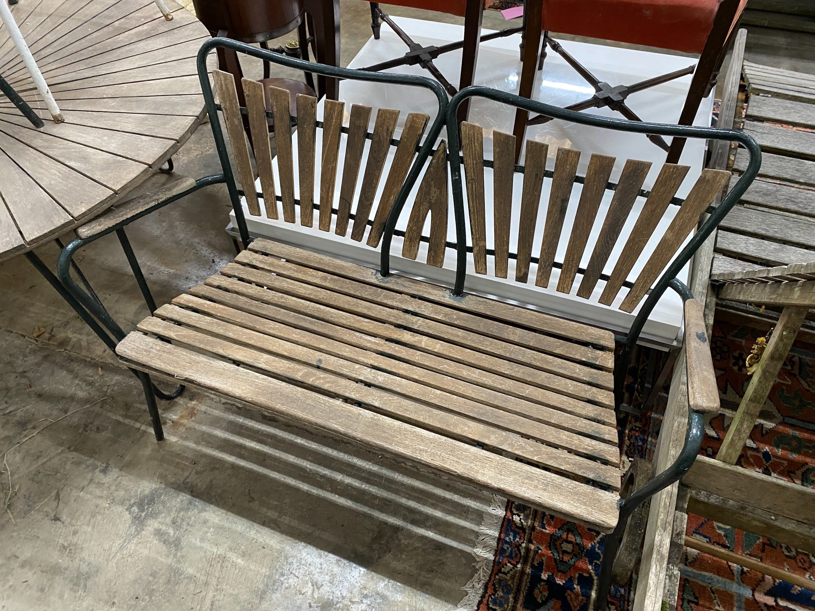 A 1950's slatted wood and wrought iron circular garden table, diameter 180cm, height 62cm, together with two elbow chairs and a bench seat